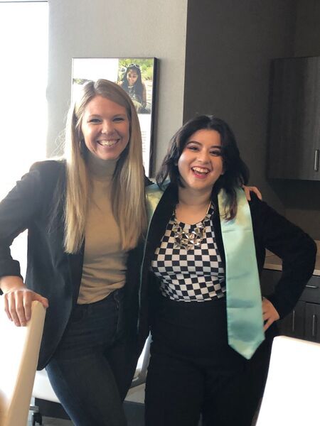 Photograph of Liz Galvez wearing her honors stole, standing with her advisor, Laura Decker.