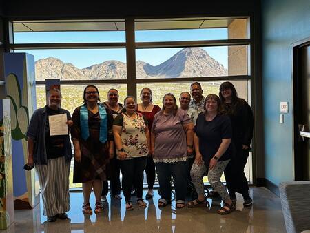 Photograph of Clarissa Puloto wearing her honors stole, standing with her family after her defense. Committee member present: Heather Lang-Cassera.